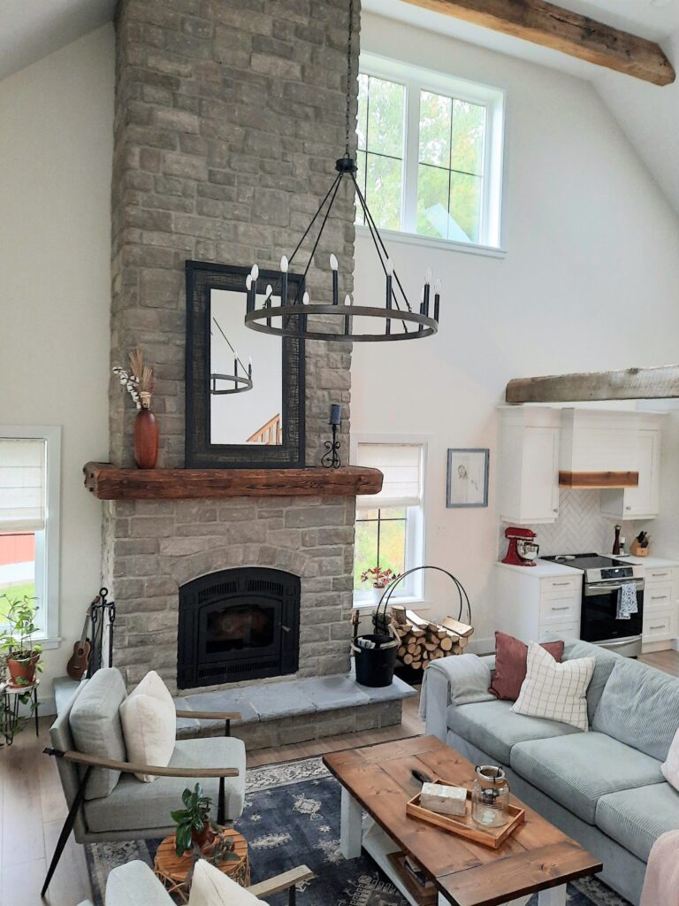 modern farmhouse living room with  floor to ceiling fire place, barn beams on ceiling and mantle and Verena Dark Wood rug by Ruggable
