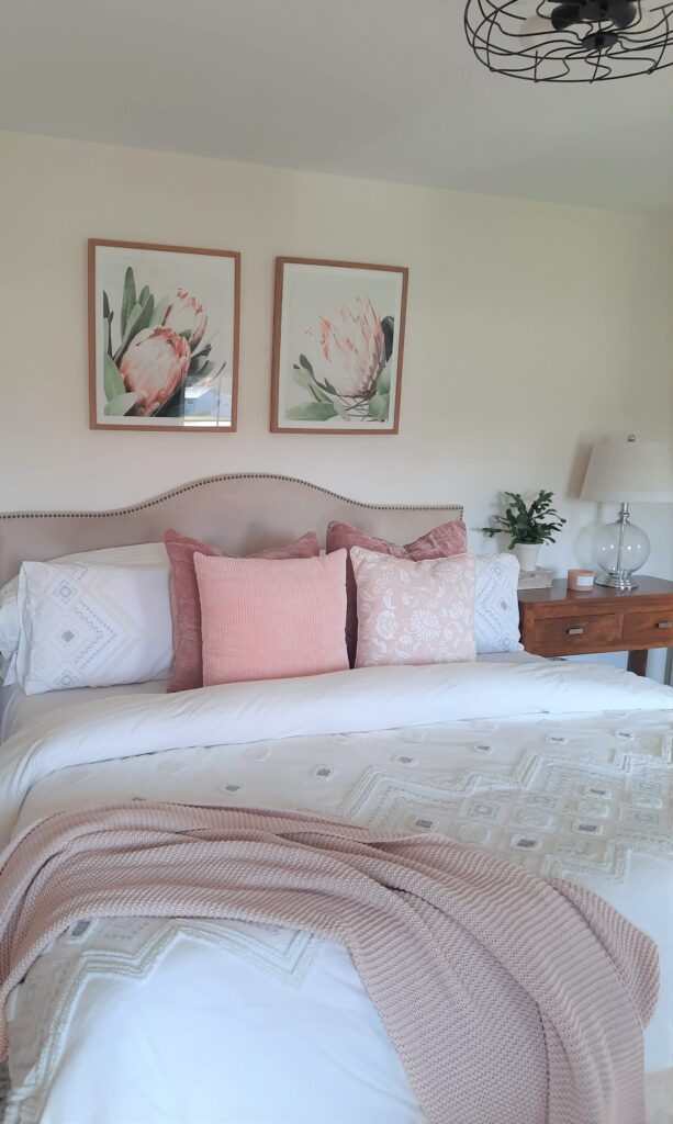 bedroom with king size bed, decorative pillows in soft pinks and greys and an urban barn duvet