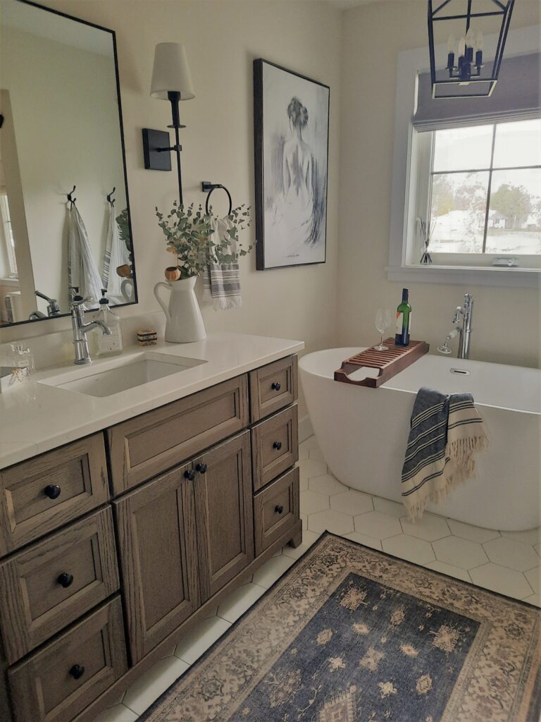 free standing vanity and free standing Wesley bathtub by Bath Depot with Verena Dark Wood rug by Ruggable and hexagon white floor tyles